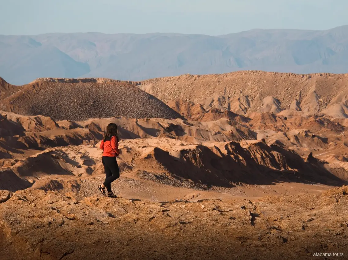 Excursions dans l'Atacama à Baltinache, randonneuse en veste rouge face aux crêtes érodées du désert