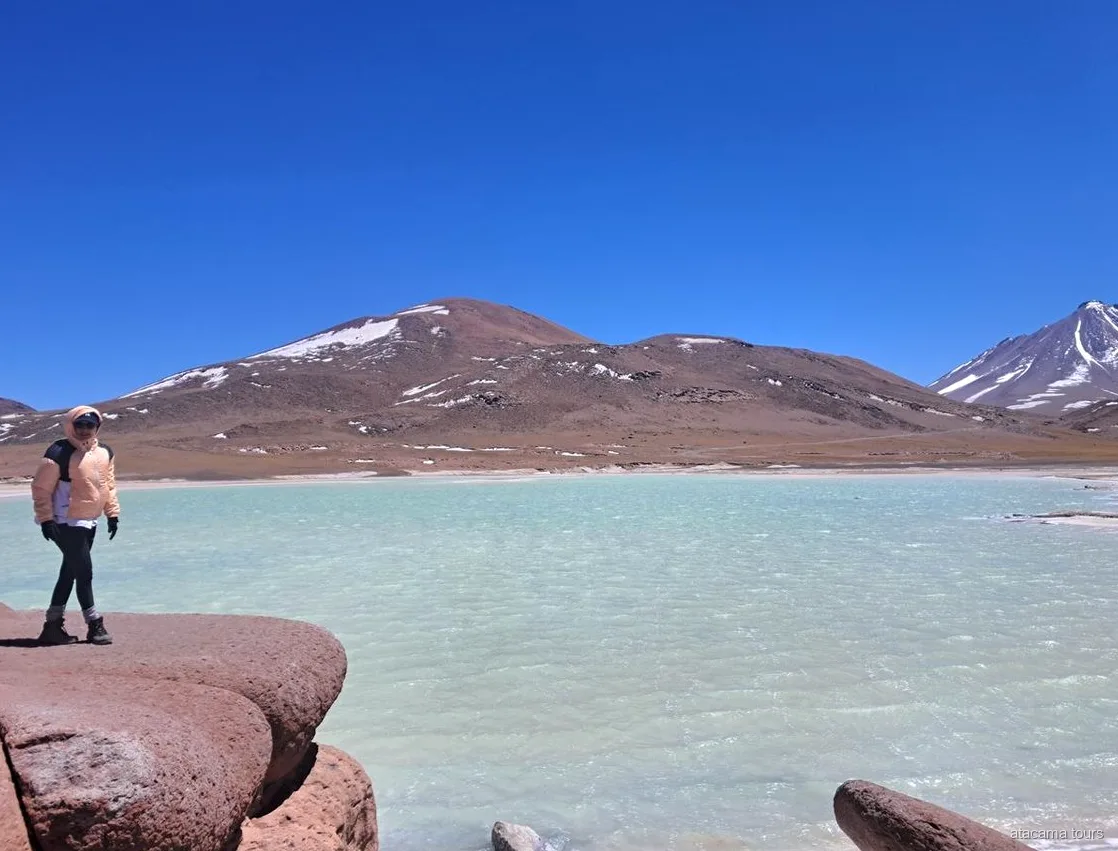 Excursions dans l'Atacama à Piedras Rojas, visiteur sur les roches rouges face à une lagune turquoise