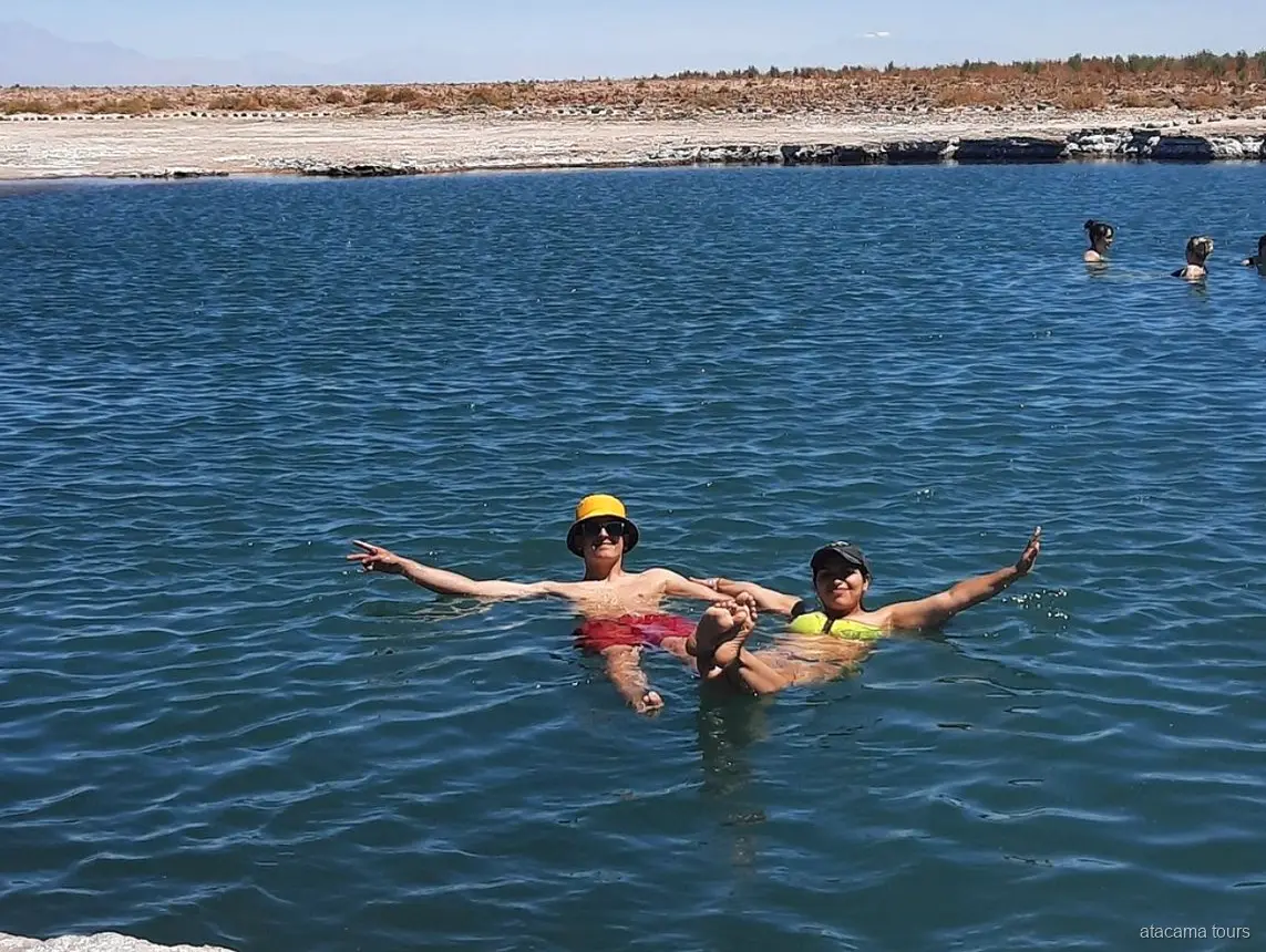 Atacama tours bij Laguna Cejar, twee bezoekers drijven met gespreide armen in het zoute blauwe water