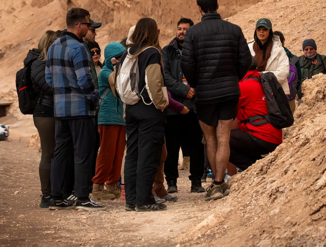 Atacama tours group in warm jackets gathered with their guide on a sandy trail in Moon Valley